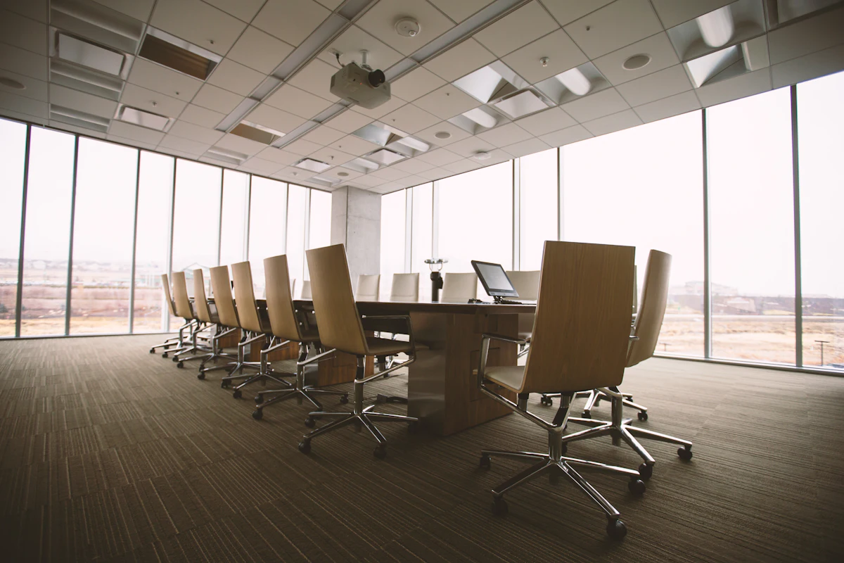 An empty boardroom with a long wooden table and city views