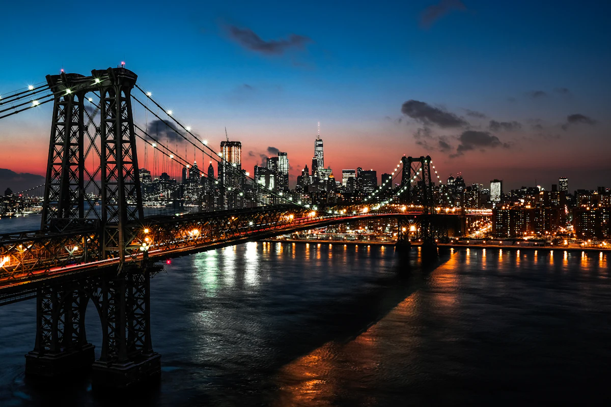 The Manhattan skyline at dusk behind the Williamsburg Bridge